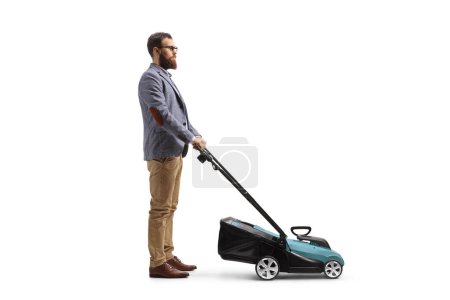 Photo for Full length profile shot of a bearded man tanding with a lawn mower isolated on white background - Royalty Free Image