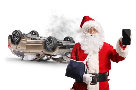 Téléchargez les photos : Père Noël avec une blessure au bras d'un accident de voiture montrant un smartphone isolé sur fond blanc - en image libre de droit