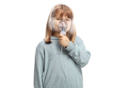 Téléchargez les photos : Petite fille utilisant un masque inhalateur portable avec brouillard de vapeur isolé sur fond blanc - en image libre de droit