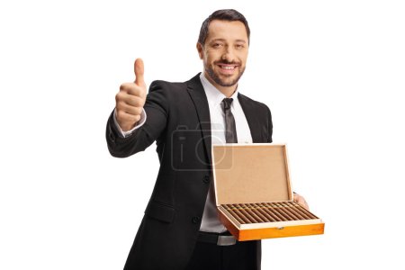 Foto de Hombre sosteniendo una caja de madera con cigarros y haciendo gestos con los pulgares hacia arriba aislado sobre fondo blanco - Imagen libre de derechos