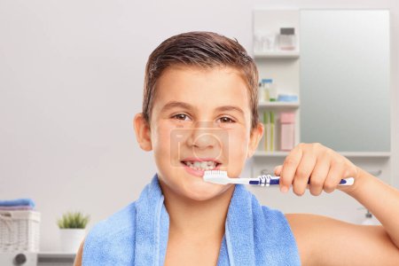 Téléchargez les photos : Petit garçon brossant les dents dans la salle de bain - en image libre de droit