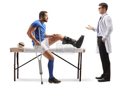 Foto de Jugador de fútbol con la pierna lesionada hablando con un médico ortopedista aislado sobre fondo blanco - Imagen libre de derechos