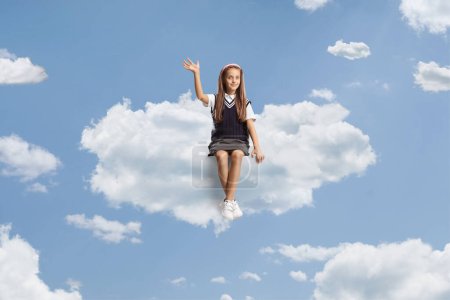 Photo for Girl in a school uniform sitting on a cloud and waving - Royalty Free Image