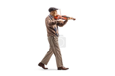Photo for Full length profile shot of an elderly man walking and playing a violin isolated on white background - Royalty Free Image