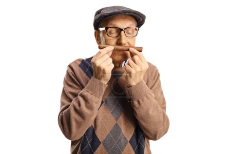 Téléchargez les photos : Homme âgé sentant un cigare isolé sur fond blanc - en image libre de droit
