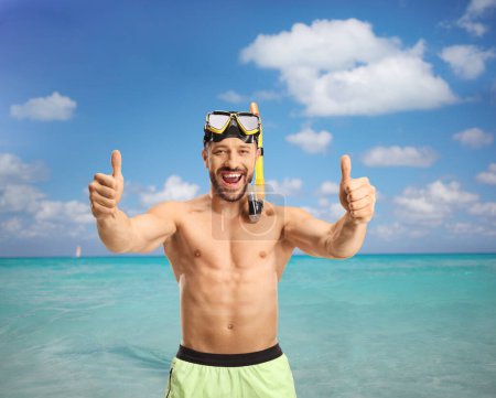 Téléchargez les photos : Homme joyeux dans la mer avec un masque de plongée montrant pouces vers le haut - en image libre de droit