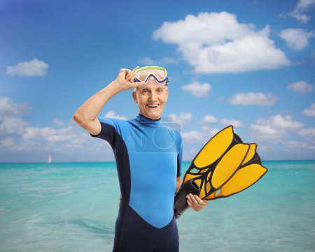 Foto de Anciano en traje de neopreno con equipo de snorkel parado frente a un mar - Imagen libre de derechos