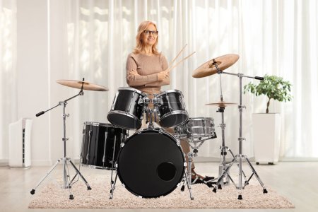 Photo for Mature female drummer posing with a drum set in a room - Royalty Free Image