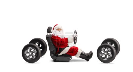 Téléchargez les photos : Père Noël dans un siège d'auto tenant un volant et regardant la caméra isolée sur fond blanc - en image libre de droit