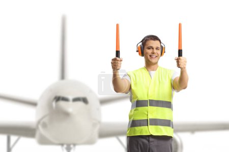 Foto de Señalización del marshaller de aeronaves con varitas delante de una aeronave - Imagen libre de derechos