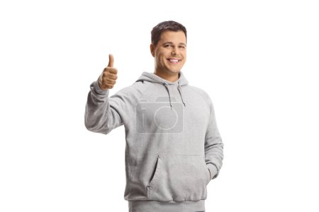 Photo for Young man in a gray hoodie showing thumbs up isolated on white background - Royalty Free Image