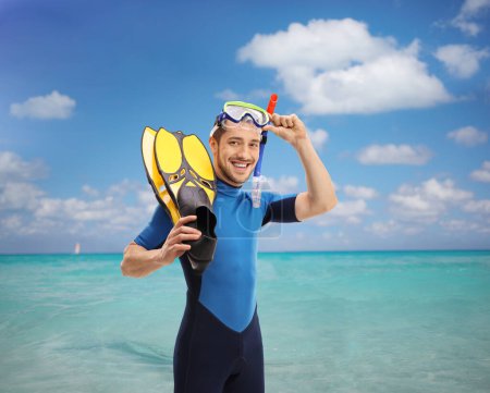 Téléchargez les photos : Homme avec équipement de plongée avec tuba regardant la caméra et debout dans la mer - en image libre de droit