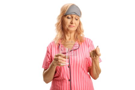 Téléchargez les photos : Femme en pyjama tenant une pilule et un verre d'eau isolé sur fond blanc - en image libre de droit