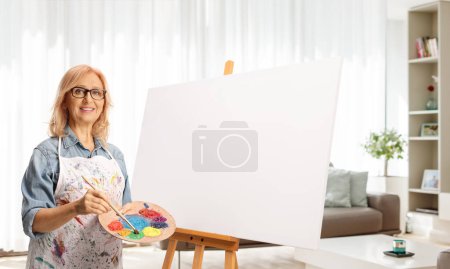 Téléchargez les photos : Femme avec une toile vierge debout dans un salon - en image libre de droit