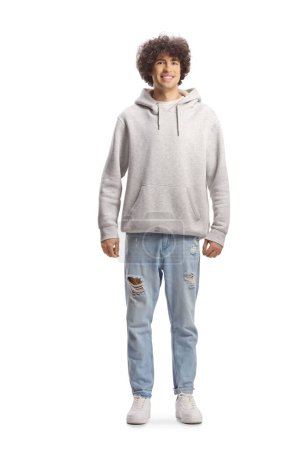 Photo for Full length portrait of a guy with curly hair in a gray hoodie and jeans isolated on white background - Royalty Free Image