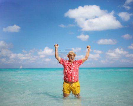 Photo for Overjoyed mature tourist on a summer holiday gesturing happiness with arms up in the sea - Royalty Free Image