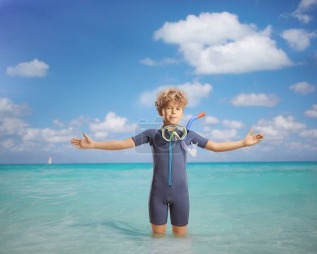 Téléchargez les photos : Garçon portant une combinaison et un masque de plongée et debout dans la mer - en image libre de droit