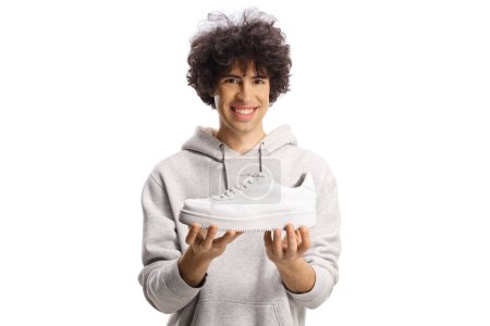 Photo for Happy young man holding a trendy white sneaker isolated on white background - Royalty Free Image