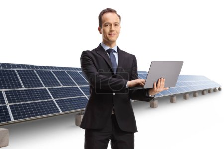 Foto de Empresario con un ordenador portátil frente a paneles solares aislados sobre fondo blanco - Imagen libre de derechos