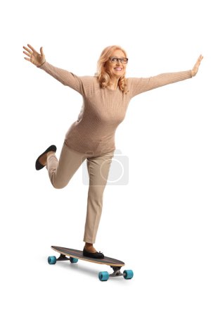 Téléchargez les photos : Femme mûre chevauchant une planche à roulettes et écartant les bras isolés sur fond blanc - en image libre de droit