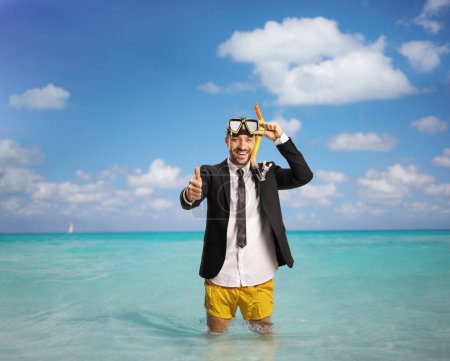 Photo for Businessman standing in the sea wearing yellow swimming shorts and a diving mask and gesturing thumbs up - Royalty Free Image