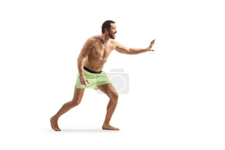 Photo for Young man in swimming shorts waiting to catch something isolated on white background - Royalty Free Image