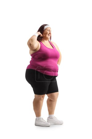 Foto de Largura completa de una mujer de talla grande en ropa deportiva de pie y sonriendo aislado sobre fondo blanco - Imagen libre de derechos