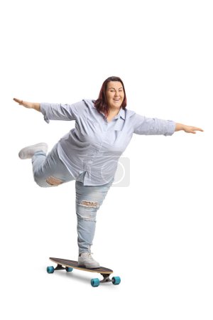 Foto de Mujer joven de talla grande montada en un monopatín y brazos extendidos aislados sobre fondo blanco - Imagen libre de derechos
