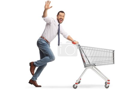 Foto de Hombre alegre corriendo con un carrito de compras y saludando a la cámara aislado sobre fondo blanco - Imagen libre de derechos