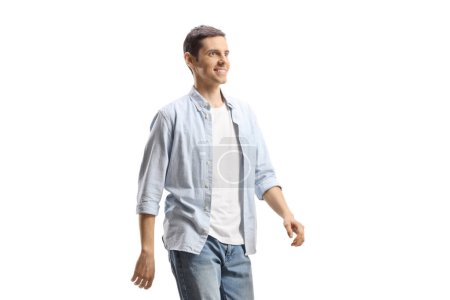 Téléchargez les photos : Jeune homme en jeans et chemise marchant isolé sur fond blanc - en image libre de droit