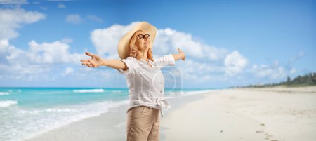 Téléchargez les photos : Femme avec un chapeau de paille profitant du soleil sur une belle plage - en image libre de droit