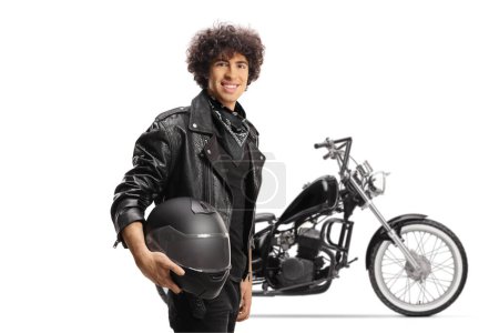 Photo for Young man with curly hair in a black leather jacket holding a helmet in front of a motorbike isolated on white background - Royalty Free Image