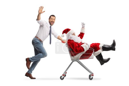 Téléchargez les photos : Happy young man running and pushing Santa in a shopping cart isolated on white background - en image libre de droit
