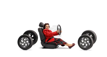 Foto de Senior woman sitting in a car seat on four tires and driving isolated on white background - Imagen libre de derechos
