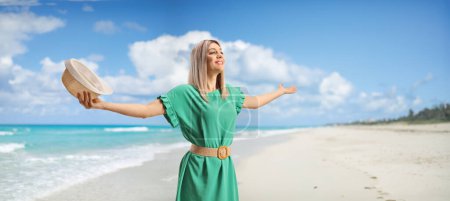 Photo for Young woman holding a straw hat and enjoying on a sandy beach - Royalty Free Image
