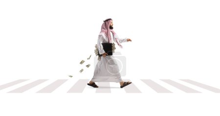 Foto de Hombre árabe Suadi caminando con un maletín lleno de dinero en un cruce de cebra peatonal aislado sobre fondo blanco - Imagen libre de derechos