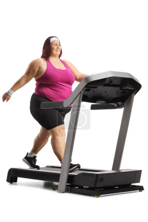 Photo for Full length shot of a plus size woman walking on a treadmill isolated on white background - Royalty Free Image