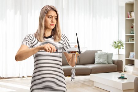 Photo for Angry young woman fixing a router in an apartment - Royalty Free Image