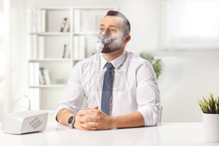 Téléchargez les photos : Jeune homme pensif utilisant un nébuliseur avec brouillard de vapeur à la maison - en image libre de droit