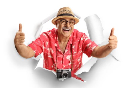 Photo for Mature male tourist peeking through a paper hole and gesturing thumbs up isolated on white background - Royalty Free Image