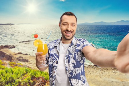 Photo for Guy holding a cocktail and taking a selfie at a beach in Greece - Royalty Free Image