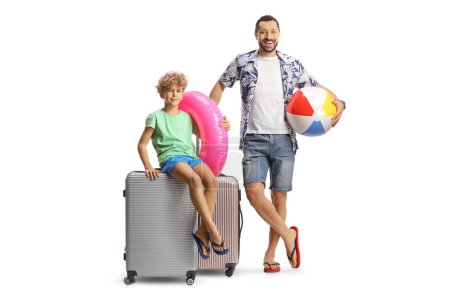 Photo for Father and son with a suitcase smiling and holding a beach ball and swimming ring isolated on white background - Royalty Free Image