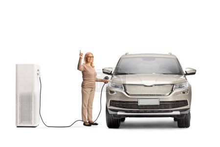 Photo for Woman charging an electric vehicle at a charging point and pointing up isolated on white background - Royalty Free Image