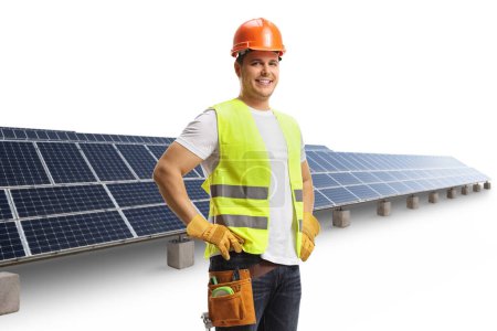 Foto de Obrero de la construcción con casco y cinturón de herramientas frente a un panel solar aislado sobre fondo blanco - Imagen libre de derechos
