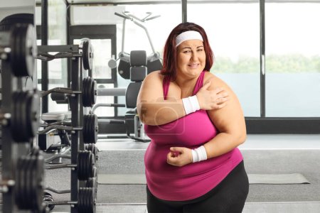 Téléchargez les photos : Femme dans une salle de gym souffrant de douleurs aux épaules - en image libre de droit