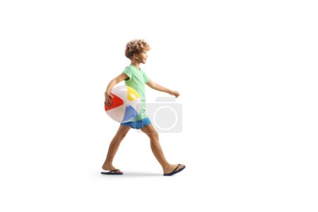 Photo for Full length profile shot of a boy walking and carrying a beach ball isolated on white background - Royalty Free Image