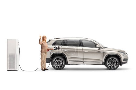 Téléchargez les photos : Femme chargeant un véhicule électrique et pointant vers le haut isolé sur fond blanc - en image libre de droit