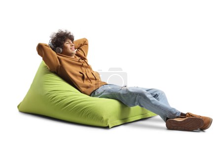 Foto de Tipo con auriculares descansando en un sillón bolsa de frijol verde aislado sobre fondo blanco - Imagen libre de derechos