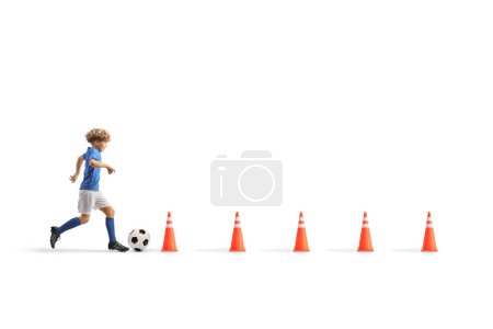 Téléchargez les photos : Plan de profil complet d'un garçon courant avec un ballon de football entre les cônes d'obstacle, entraînement à l'agilité, isolé sur fond blanc - en image libre de droit