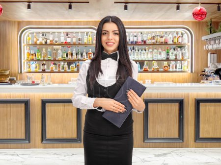 Photo for Waitress holding a menu and standing by a bar - Royalty Free Image